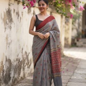 Woman wearing a grey cotton saree with rust motifs and black blouse