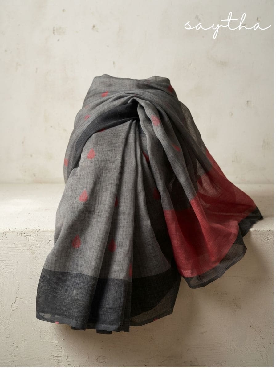 Woman wearing a grey cotton saree with rust motifs and black blouse